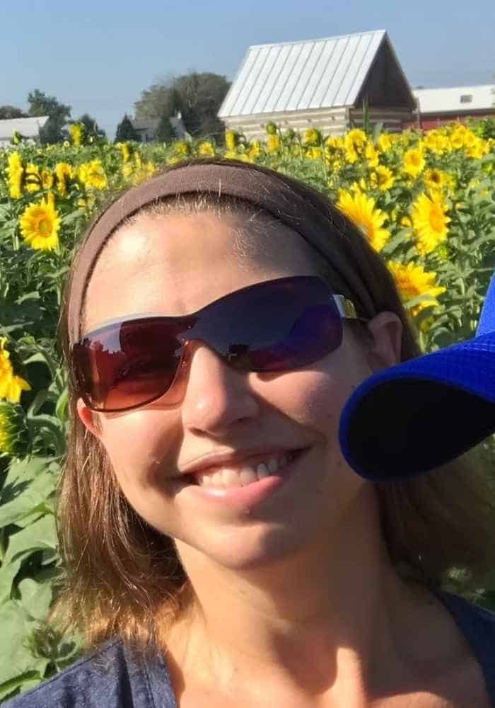 Woman holding child standing in a sunflower field on a farm