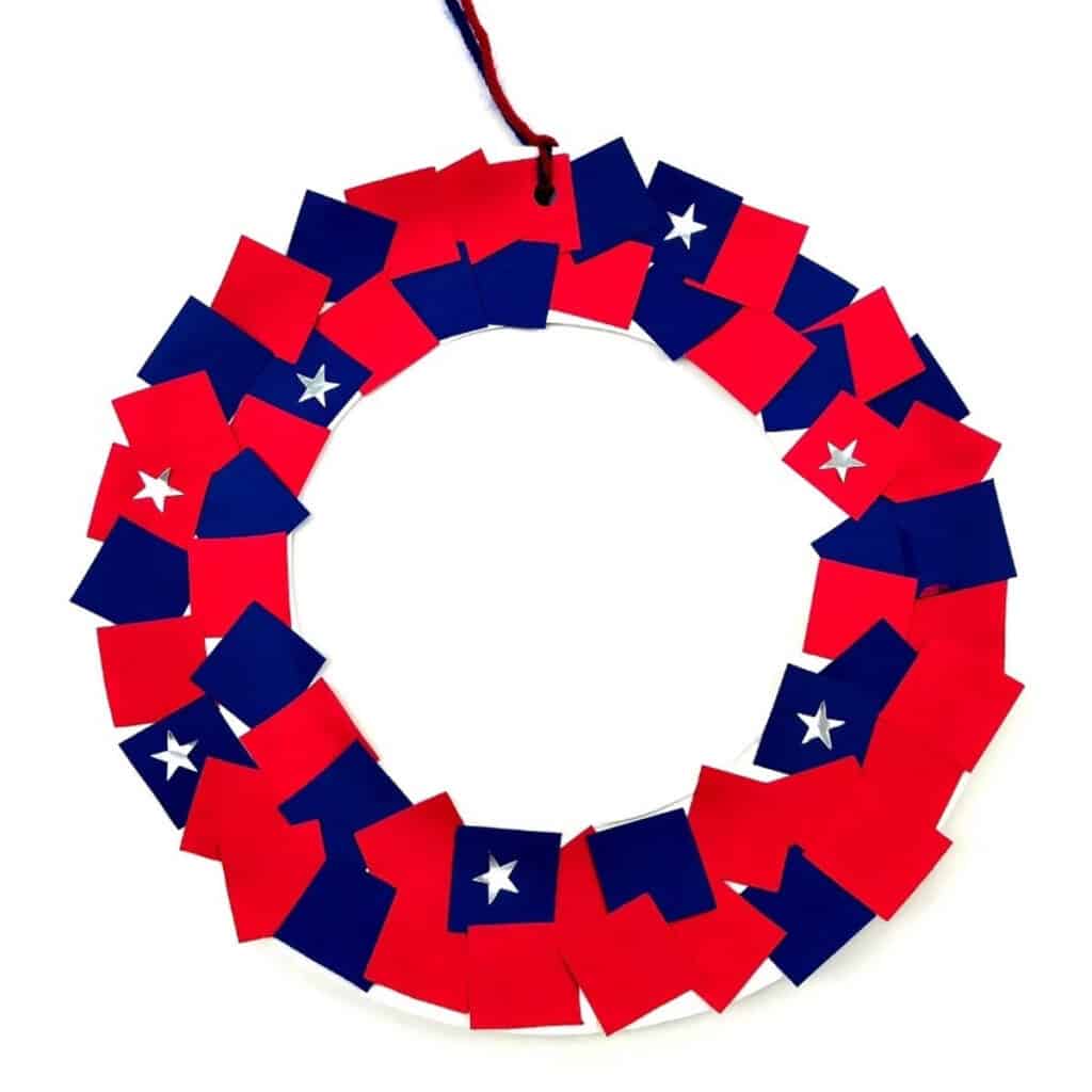 patriotic wreath craft with red and blue paper with white stars hanging from yarn